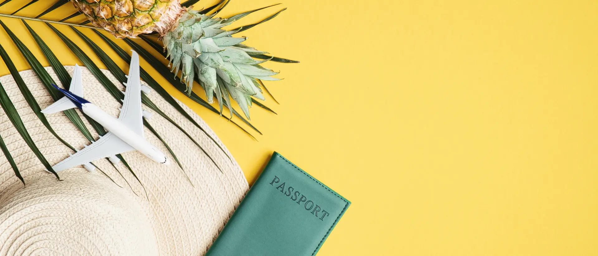 Flat lay of travel accessories with pineapple and passport