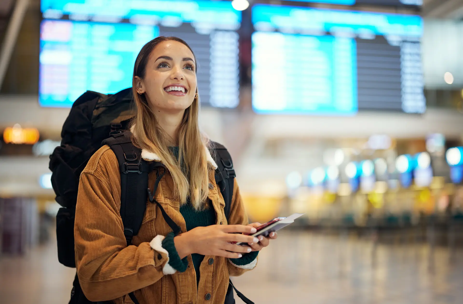 Woman traveler with backpack holding passport and flight ticket at airport