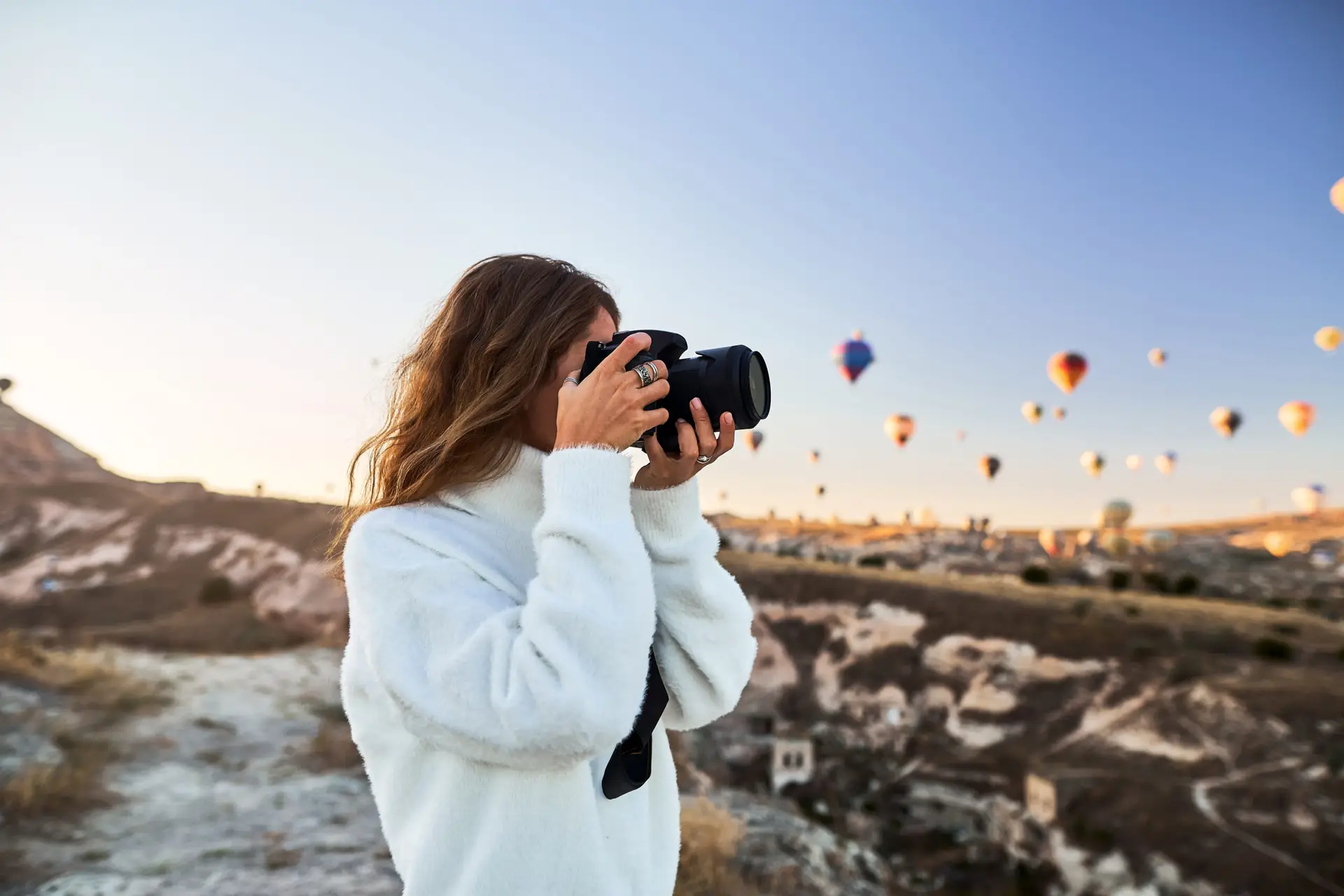 Female tourist photographing hot air balloons in Cappadocia