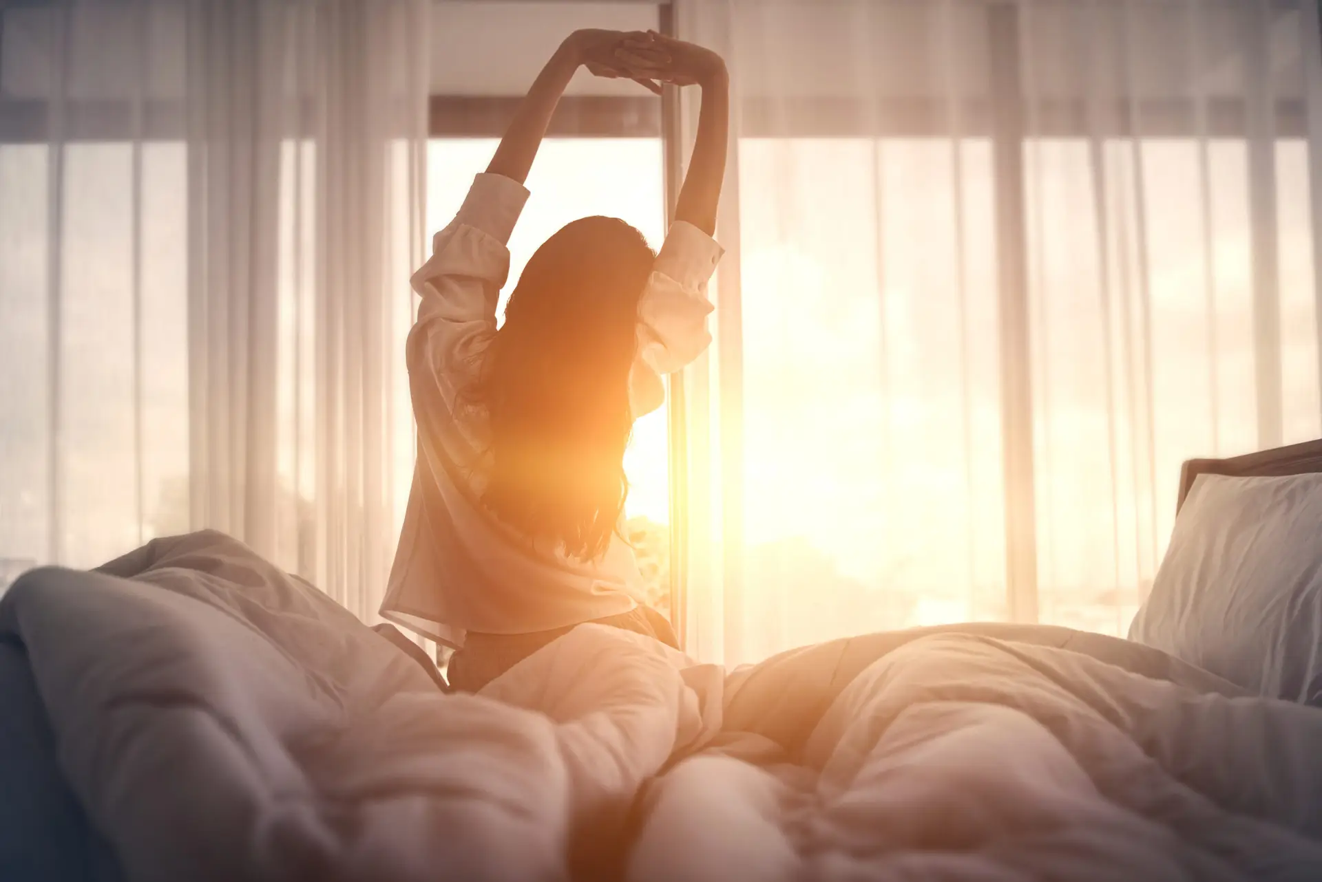Woman stretching hands in bed after wake up in the morning