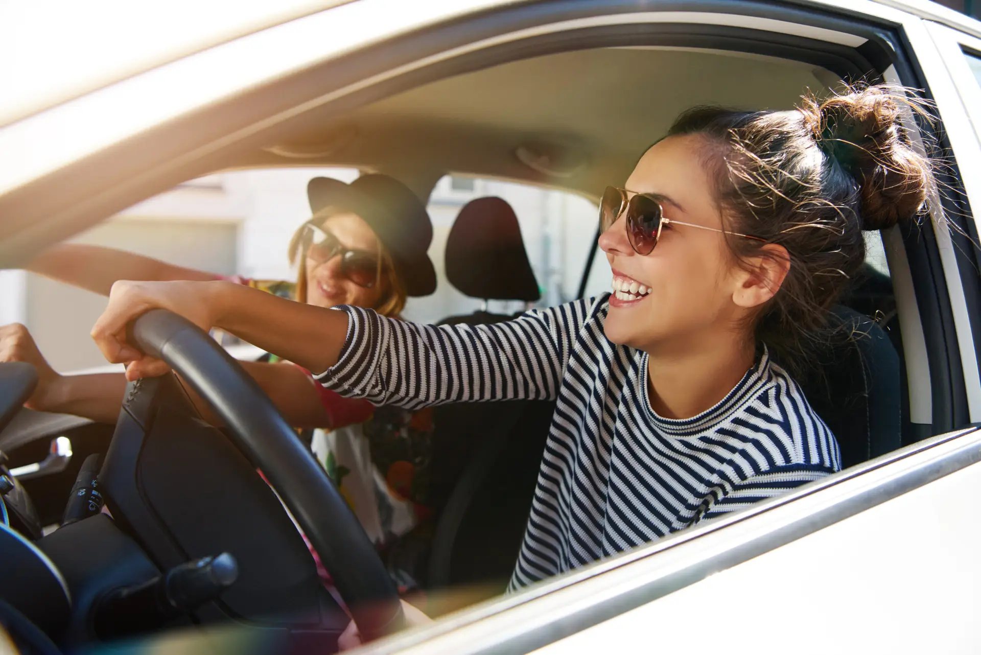 Two girls smiling and driving toward their weekend staycation