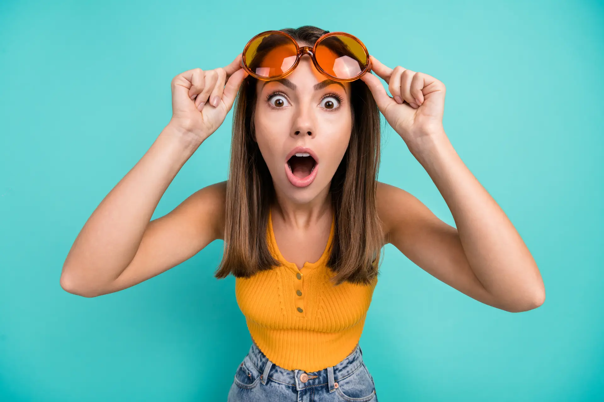 Astonished young woman on teal background