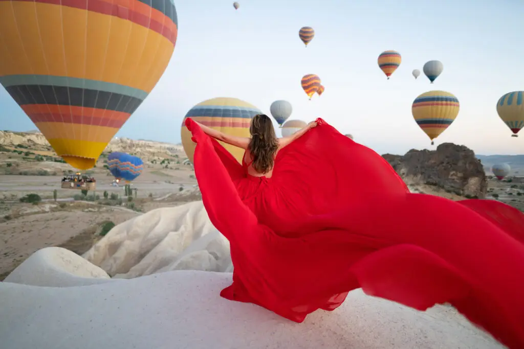 Woman in flying dress with hot air balloons in Cappadocia