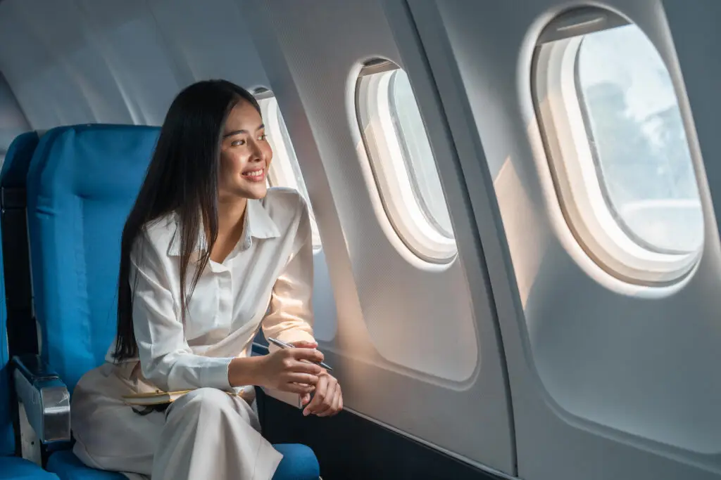 Asian woman looking out the window of an airplane