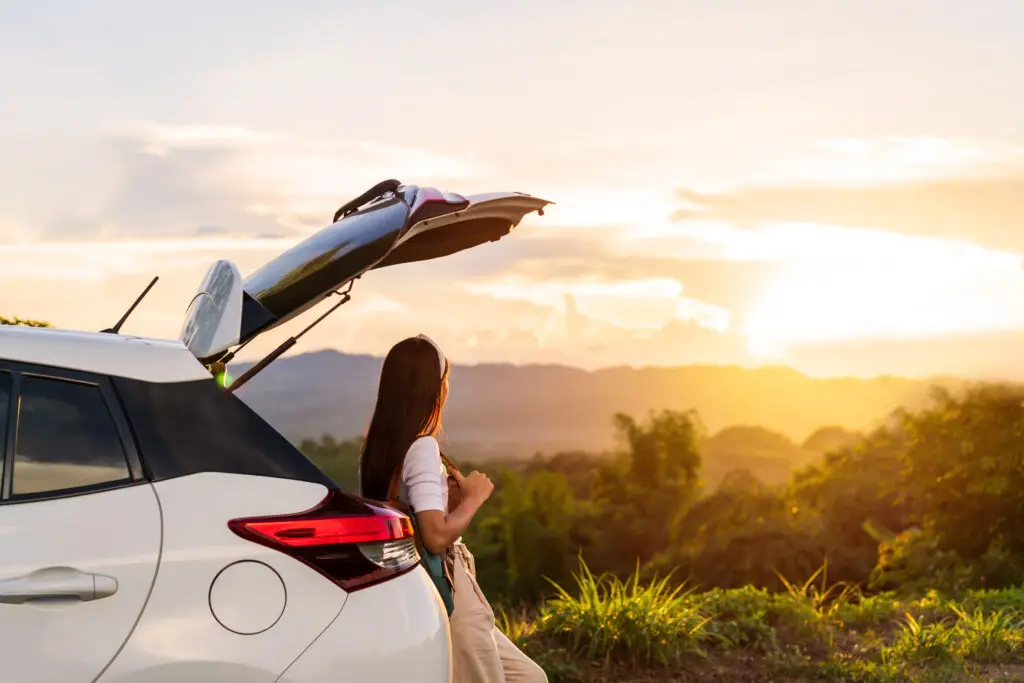 Young woman on road trip watching mountain sunrise