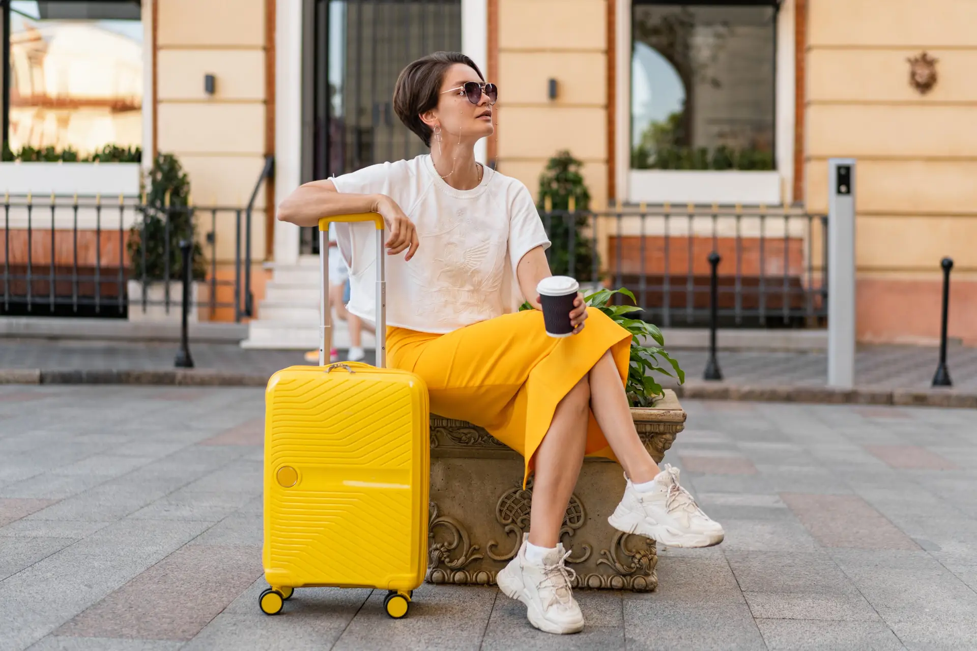 stylish woman traveling with yellow suitcase in Europe