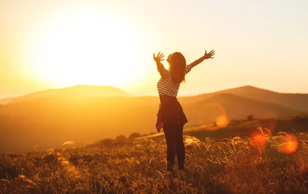 women taking a big breath in the beauty of nature while traveling solo
